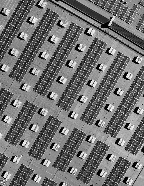 Luftaufnahme eines Gewerbedachs in Schleswig-Holstein, das mit Reihen von Photovoltaik-Solarmodulen und quadratischen Strukturen bedeckt ist.